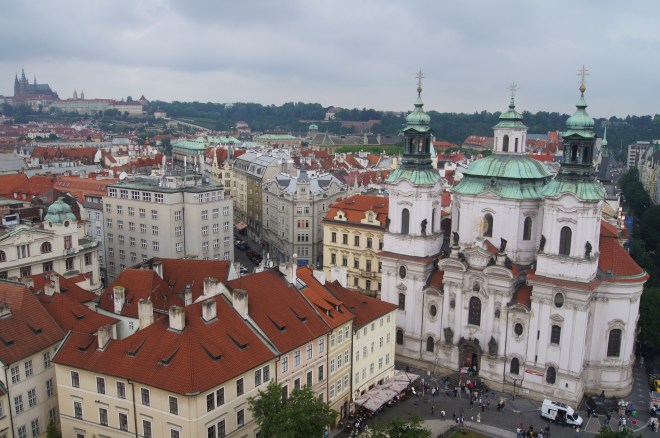 The Church of Saint Nicholas is in the foreground and the Castle Quarter across the Vltava River in the distance.